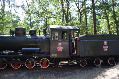 Czarna lokomotywa parowa z czerwonymi obramowaniami kół i napisem 