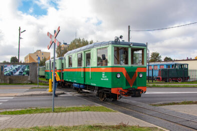 Zielony wagon kolejki wąskotorowej z czerwonym pasem i białym 