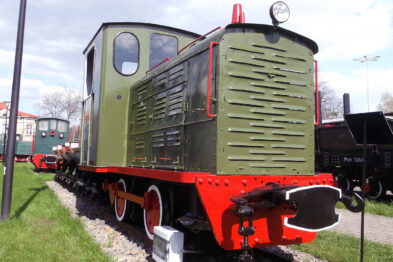 Odrestaurowana lokomotywa spalinowa WLs50-1630 stoi na torze o szerokości 750 mm; jej karoseria jest pomalowana na zielono z czerwonymi elementami na przedzie i zderzakach. Maszyna posiada jedną kabinę z oknami, reflektor na przedniej ściance oraz symetrycznie rozmieszczone żaluzje boczne. W tle widoczne są inne pojazdy szynowe i drzewa.
