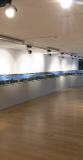 W przestronnej sali na ścianie umieszczona jest długa, panoramiczna makietą kolejową przedstawiająca krajobraz z torami i modelami pociągów. Sala posiada drewnianą podłogę i jest dobrze oświetlona za pomocą wielu punktowych świateł sufitowych. Z prawej strony znajduje się niewielkie stanowisko z ekranem i innym wyposażeniem, które wydaje się być częścią wystawy interaktywnej.