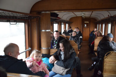 Wnętrze wagonu osobowego 1Aw. Pasażerowie: dorośli i dzieci w trakcie wycieczki