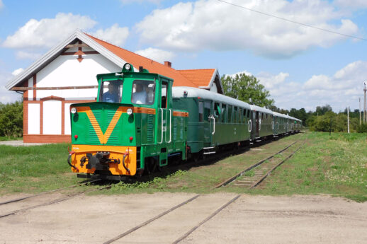 Zielona lokomotywa z wagonami stoi na stacji