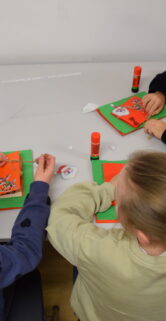 Na zdjęciu trójka dzieci wykonująca prace plastyczne